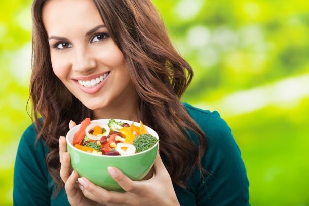 portrait of woman holding bowl of veggies