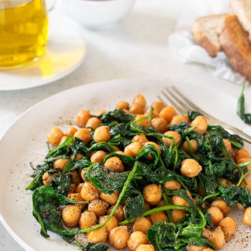 Plate of Espinacas con Garbanzos, a Spanish dish of chickpeas sautéed with spinach, seasoned with paprika, and drizzled with olive oil.