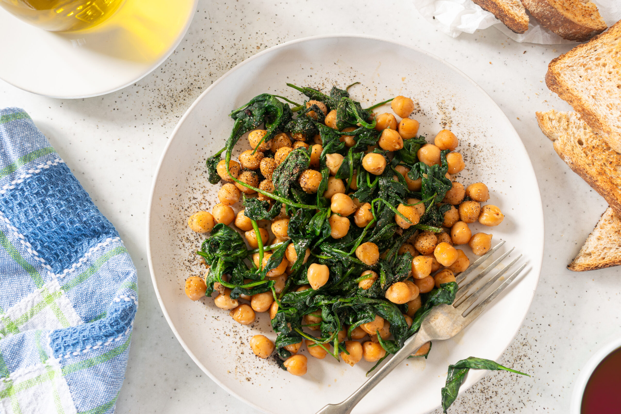 Overhead view of Espinacas con Garbanzos, Spanish chickpeas with spinach, served with toasted bread and olive oil.