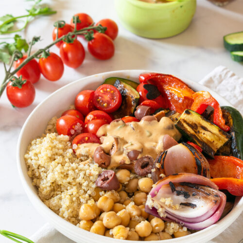 Mediterranean quinoa bowl with grilled vegetables, chickpeas, olives, and tahini sauce