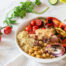 Quinoa bowl with grilled vegetables, chickpeas, olives, and lemon tahini sauce