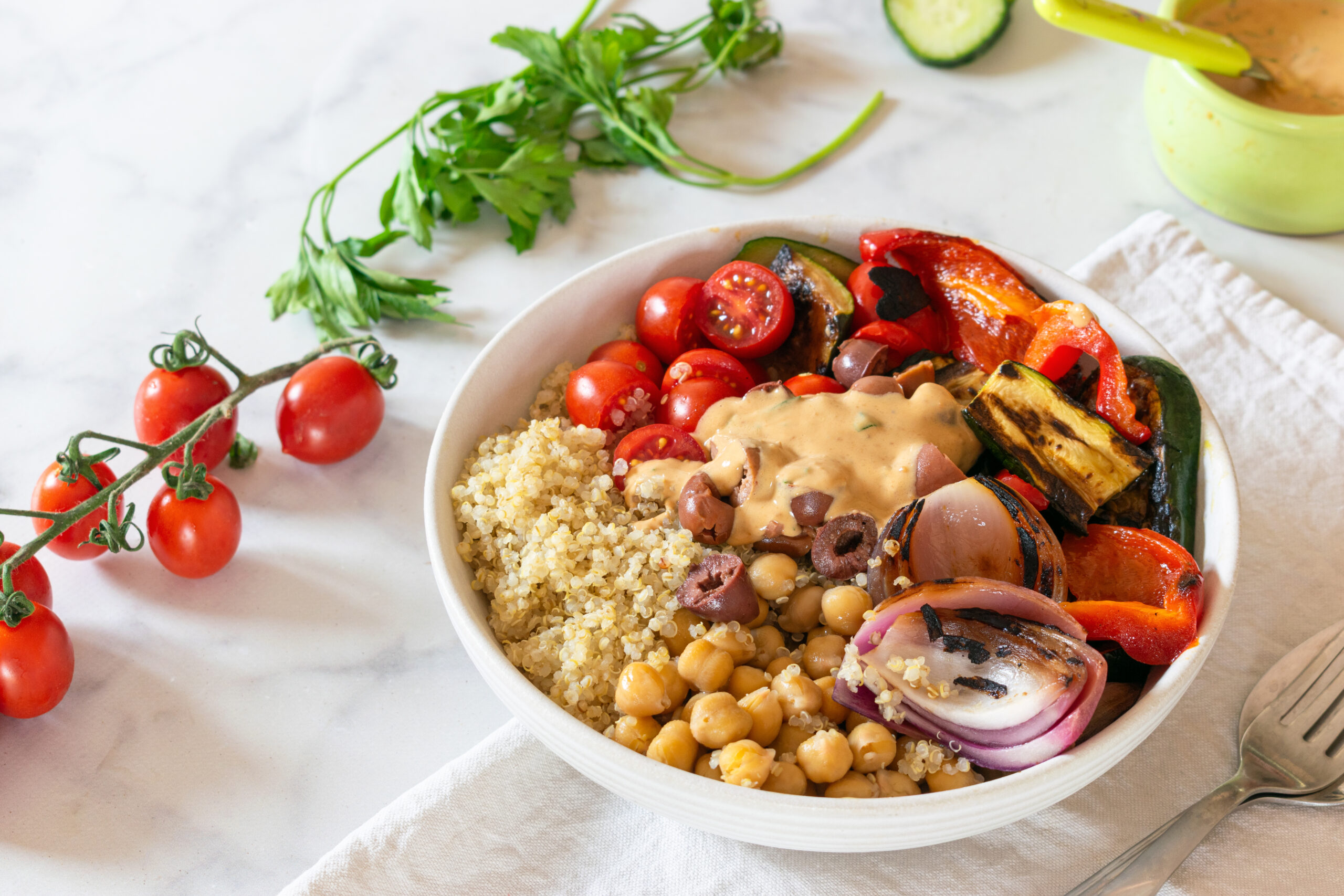 Quinoa bowl with grilled vegetables, chickpeas, olives, and lemon tahini sauce